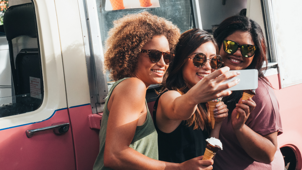 Group of smiling women taking a selfie in front of the Six Swirls ice cream truck during an office party, capturing a fun and memorable team moment.