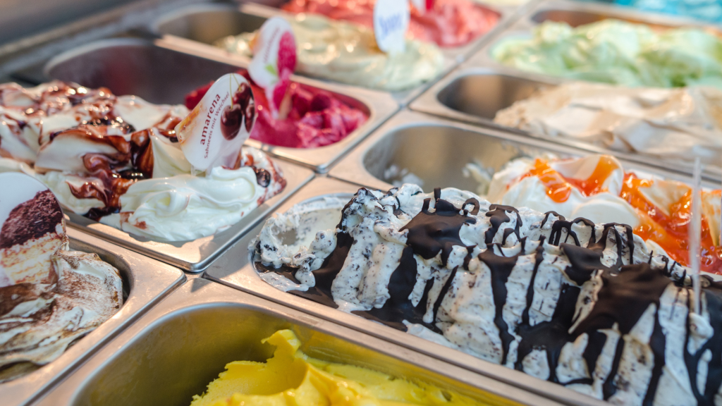 Assorted ice cream flavours displayed in a refrigerated case inside the Six Swirls ice cream truck, featuring vibrant colors and a variety of options like chocolate, mango, and berry swirl.